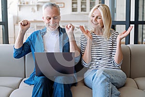 Happy mature spouses celebrating winning, reading unbelievable news