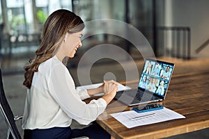 Happy mature team leader having hybrid office group meeting video call.