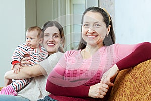 Happy mature woman and adult daughter with baby