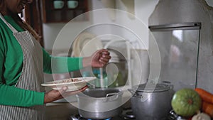 Happy mature woman cooking in old vintage kitchen - Latin female preparing beans soup at home