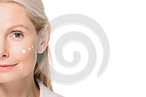 happy mature woman with cosmetic cream dots on face