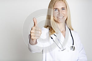 Happy mature woman doctor in uniform with thumb up