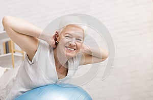 Happy mature woman doing exercises with fitness ball