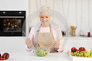 Happy Mature Woman Enjoying Cooking Preparing Healthy Salad In Kitchen