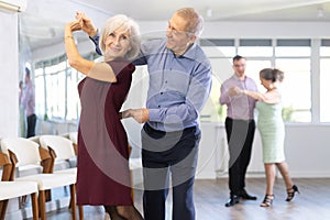 Happy mature woman enjoying impassioned merengue with male partner in dance class. Social dancing concept