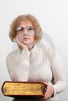 Happy mature woman with glasses holding old red paperback book Bible