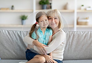 Happy mature woman and granddaughter hugging and posing