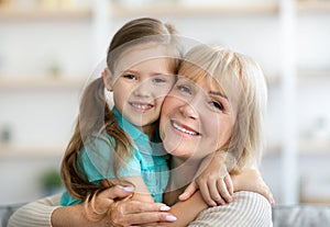 Happy mature woman and granddaughter hugging and posing