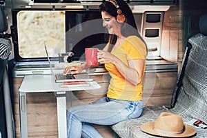 Happy mature woman having fun using computer laptop inside mini camper van - Focus on face