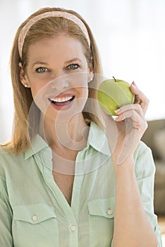 Happy Mature Woman Holding Granny Smith Apple At Home