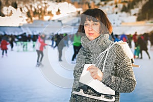 Happy mature woman holds skates at Medeo ice rink