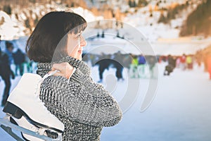 Happy mature woman holds skates at Medeo ice rink