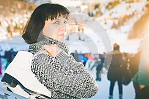 Happy mature woman holds skates at Medeo ice rink