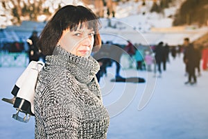 Happy mature woman holds skates at Medeo ice rink