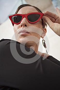 Vertical portrait of happy and cheerful mature woman outdoor, wearing retro red sunglasses.