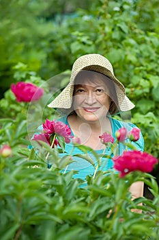 Happy mature woman in paeony plant photo