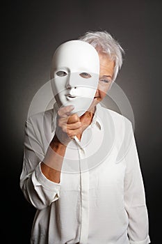 Happy mature woman peeking from behind mask