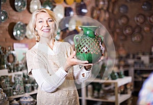 Happy mature woman posing with ceramic cookware