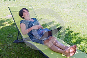 Happy mature woman relaxing resting on the deck chair in garden