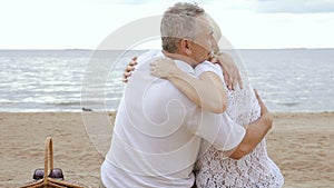 Happy mature woman and retired man hugging on seaside.