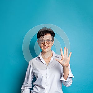 Happy mature woman with short hair counting and showing five with fingers on blue background