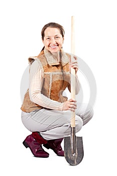 Happy mature woman sits with spade