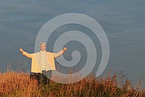 Happy mature woman with spread arms in nature