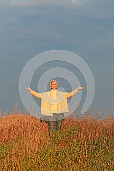 Happy mature woman with spread arms in nature