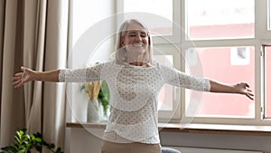 Happy mature woman standing with arms outstretched, enjoying life