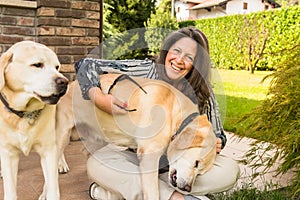 Happy mature woman with two labrador retriver dogs in the garden