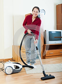 Happy mature woman with vacuum cleaner
