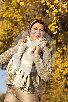 Happy matured woman in front of yellow autumn leaves