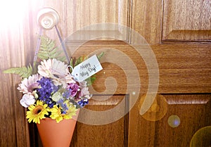 Happy May Day gift of flowers on door with lens flare.