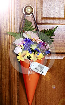 Happy May Day gift of flowers on door with lens flare.