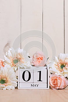 Happy May Day white block wood calendar decorated with spring flowers on wood table.