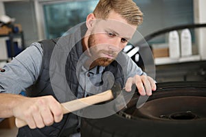 happy mechanic fixing car tire at repair shop