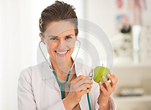 Happy medical doctor woman examining apple