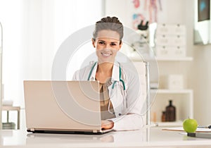 Happy medical doctor woman working on laptop