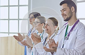 Happy medical team comprising male and female doctors smiling broadly and giving a thumbs up of success and hope