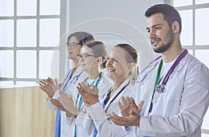 Happy medical team comprising male and female doctors smiling broadly and giving a thumbs up of success and hope