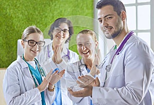 Happy medical team comprising male and female doctors smiling broadly and giving a thumbs up of success and hope