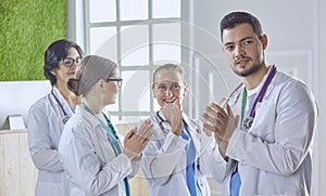 Happy medical team comprising male and female doctors smiling broadly and giving a thumbs up of success and hope