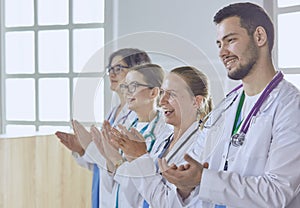 Happy medical team comprising male and female doctors smiling broadly and giving a thumbs up of success and hope