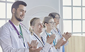 Happy medical team comprising male and female doctors smiling broadly and giving a thumbs up of success and hope