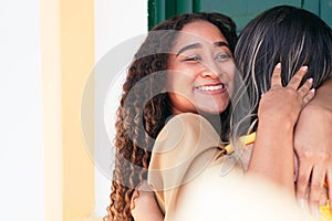 Happy meeting of two friends hugging on the street. Smiling friends laughing and hugging in the center of the city