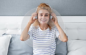 Happy melomaniac woman listening to music on bed, music. Relaxing woman enjoying music