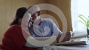 Happy memories, a loving elderly husband enjoys family life kisses his beloved cheerful elderly wife while watching a