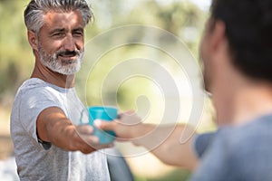 happy men drinking tea in autumn forest