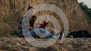 Happy man and woman relaxing on beach. Cheerful girl taking photo on smartphone