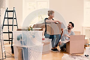 Happy man and woman unpacking stuff from cartoon boxes while furnishing interior photo